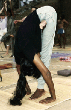 Actitud avanzada del árbol Actitud avanzada del árbol-Mujer de pie doblada la eesplada tocandose el pecho con las rodillas