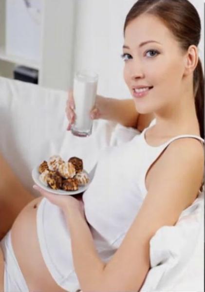 Una mujer embarazada sentada en su cama.